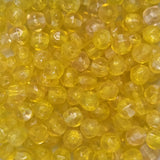 Close-up of yellow beads with a threading hole showing for the purpose of stringing jewelry