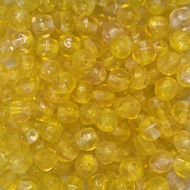 Close-up of yellow beads with a threading hole showing for the purpose of stringing jewelry