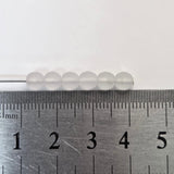 Metal ruler next to a row of white beads on a light gray background