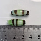 Two striped beads next to a ruler on a white background