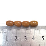 Four brown beads on a ruler for size reference