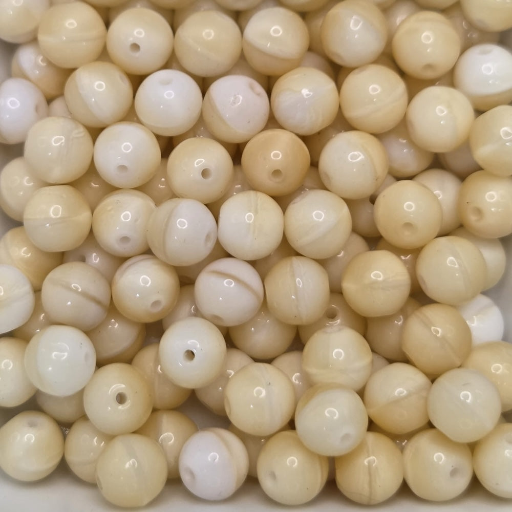 a collection of beige round glass beads with holes for threading
