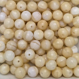 a collection of beige round glass beads with holes for threading