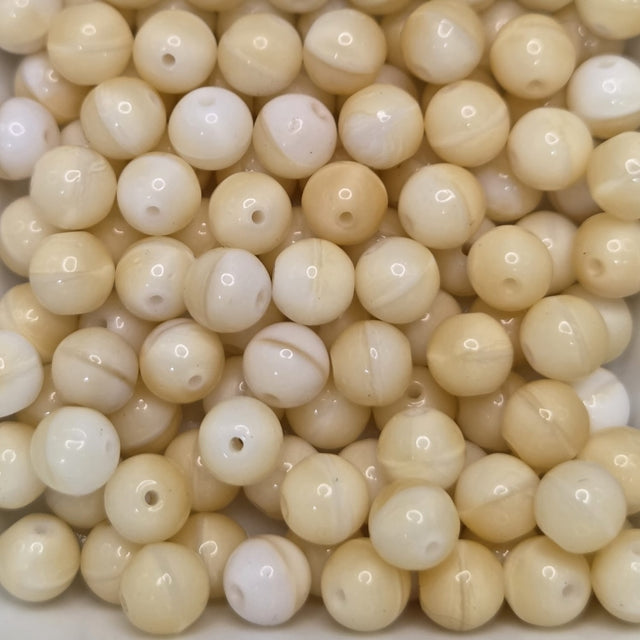 a collection of beige round glass beads with holes for threading