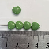 Green beads on a metal rod with a ruler for scale on a white background