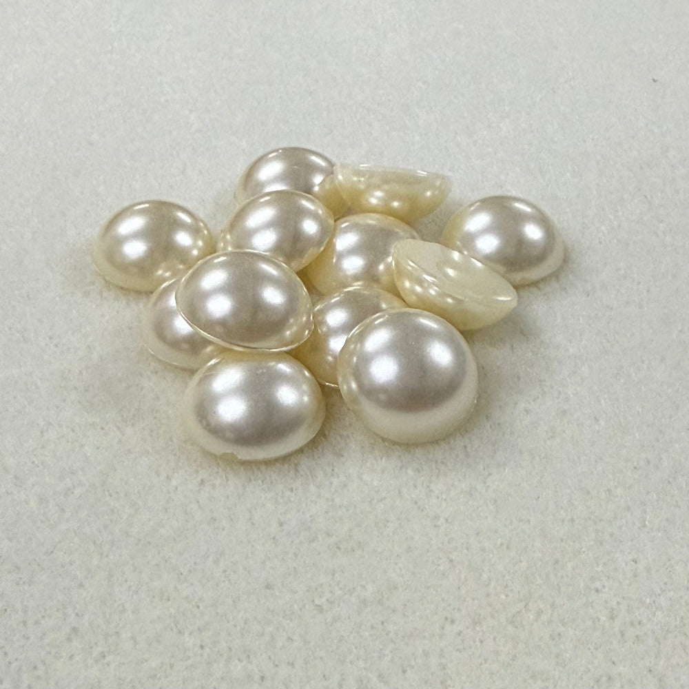 Vintage pearl flat back cabochons on a beige surface