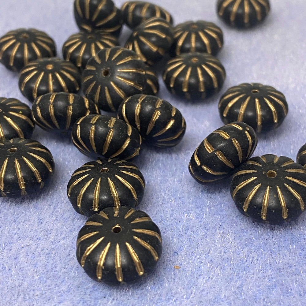 Black beads with gold patterns on a light blue background