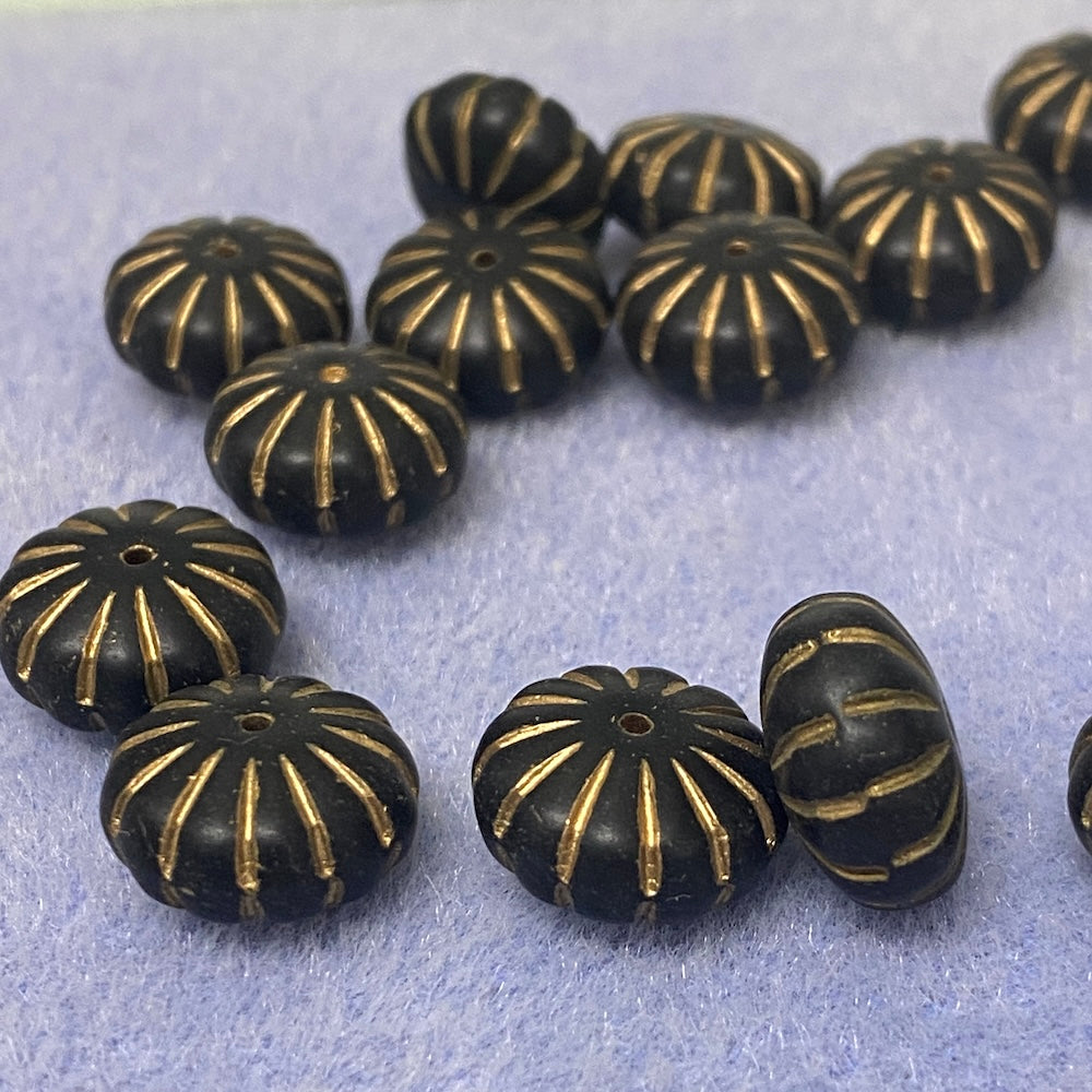 Black beads with gold patterns on a light gray background