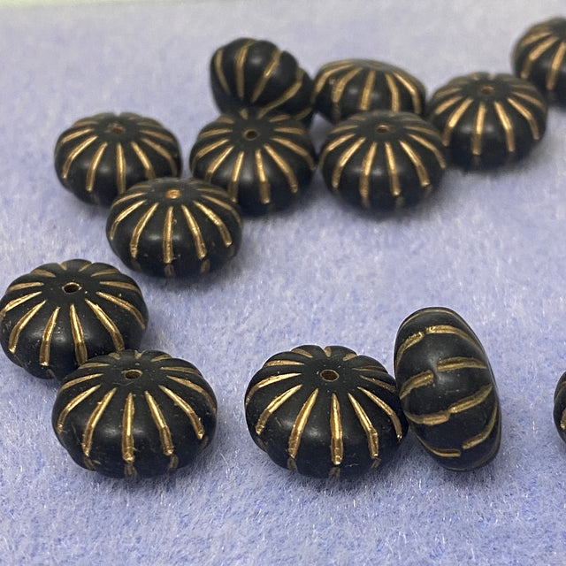 Black beads with gold patterns on a light gray background