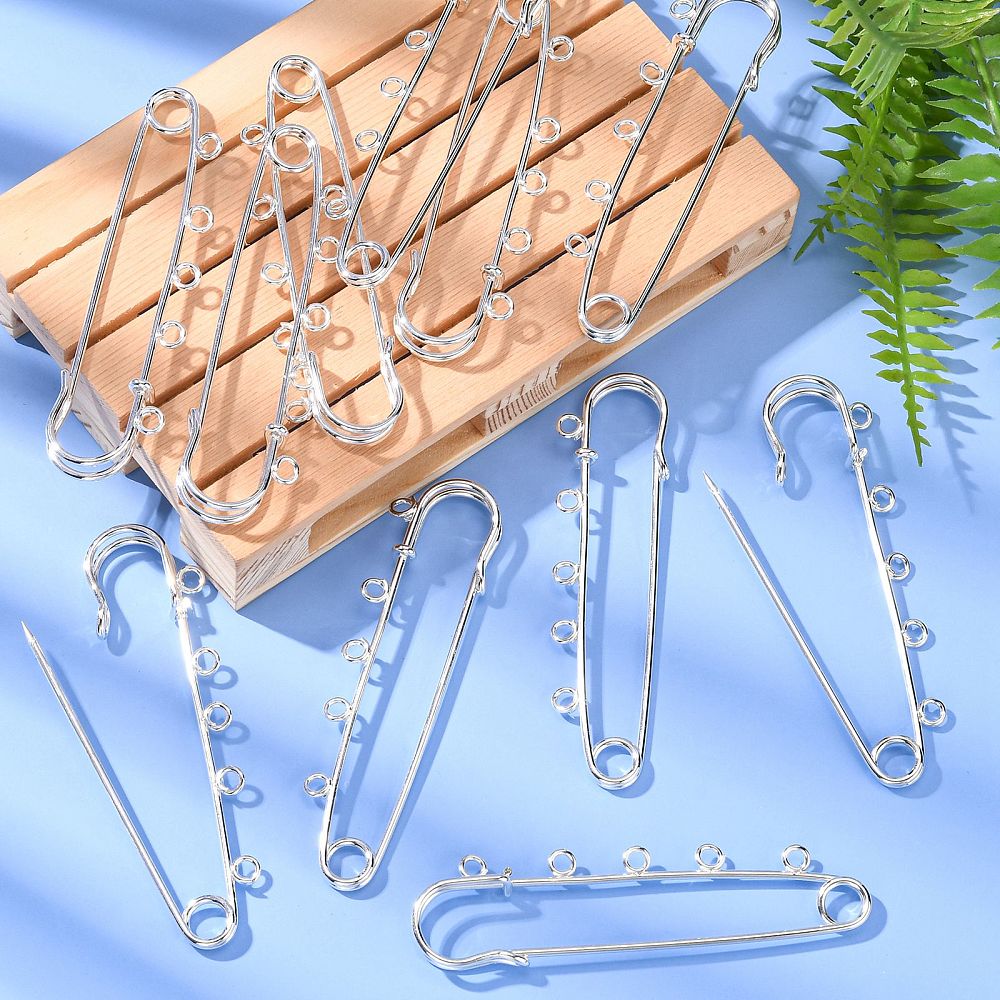 Kilt Pins in silver tone with 5 loops for threading beads and charms on a blue background