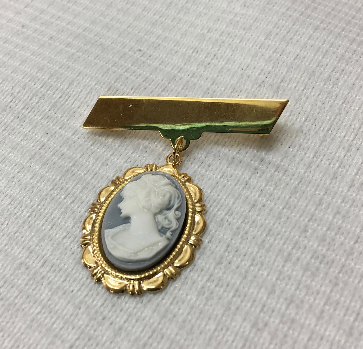 Gold brooch with a cameo pendant on a light gray background