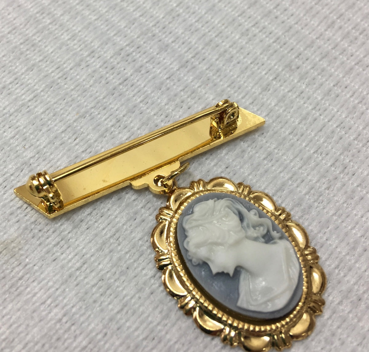 Gold brooch with a cameo featuring a profile of a woman on a light gray background