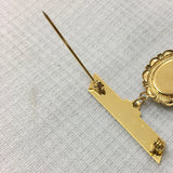 Gold-colored decorative pin on a textured white background