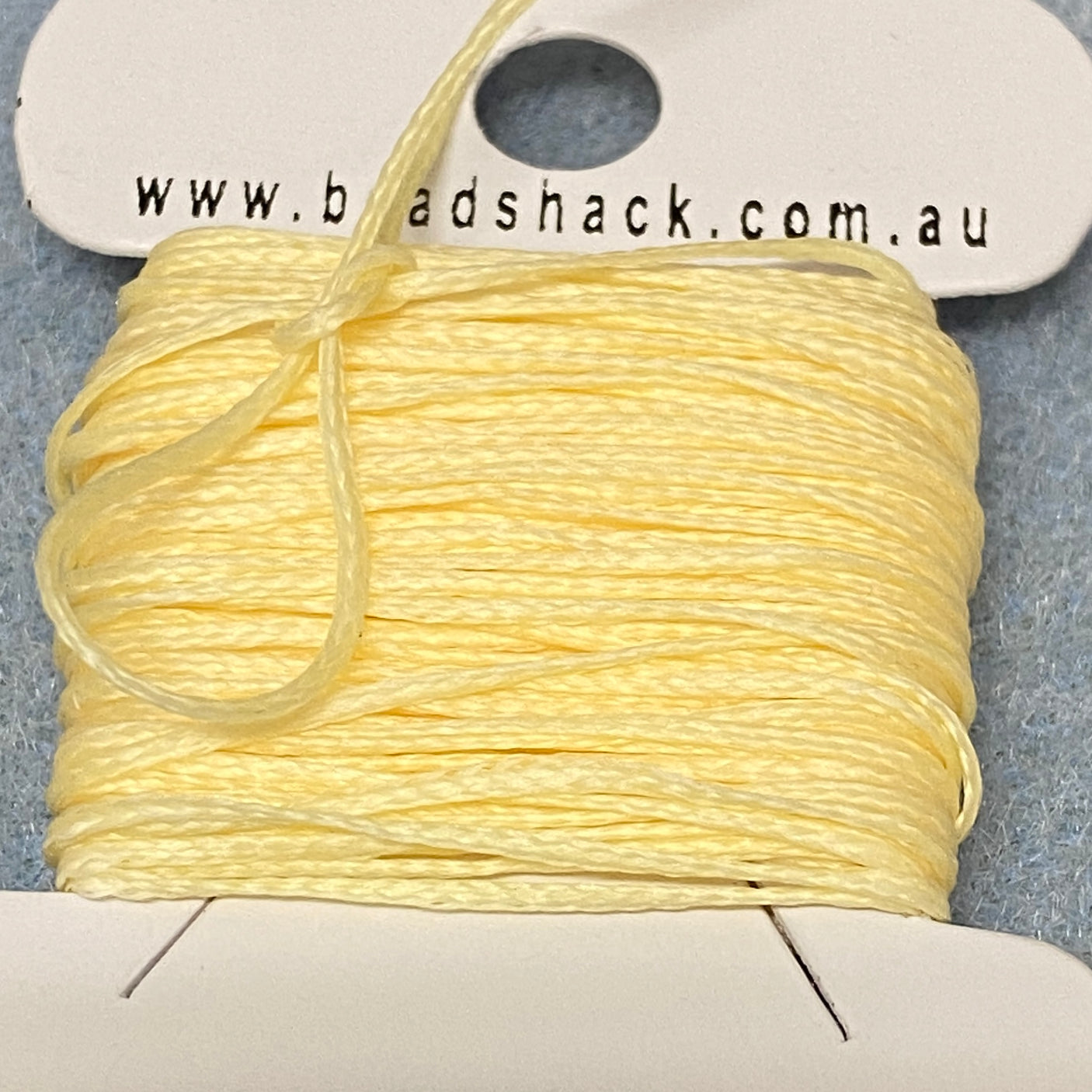 A spool of yellow flat waxed cord on a white card, with the brand name 'Bead Shack' displayed.
