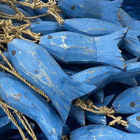 A cluster of hand-painted blue wooden fish decorations connected with ropes