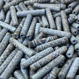 Close-up of a pile of blue cylindrical vintage ceramic beads with intricate patterns.