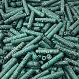 Close-up of a pile of green cylindrical vintage ceramic beads with intricate patterns.
