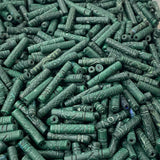 Close-up of a pile of green cylindrical vintage ceramic beads with intricate patterns.