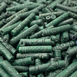 Close-up of a pile of green cylindrical vintage ceramic beads with intricate patterns.