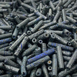 Close-up of a pile of dark blue cylindrical vintage ceramic beads with intricate patterns.