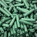 Close-up of a pile of green cylindrical vintage ceramic beads with intricate patterns.