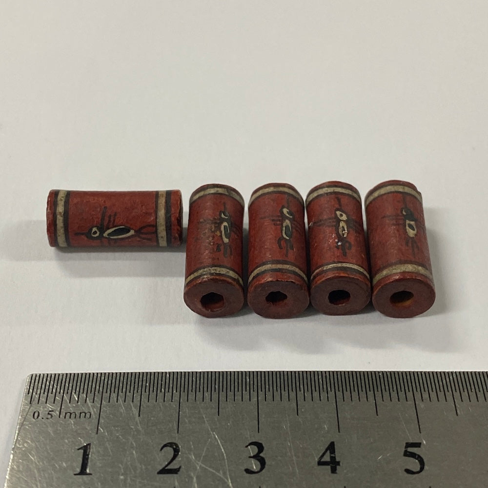 Set of cylindrical vintage ceramic beads with decorative elements on a white background, measured against a ruler.