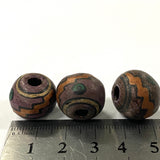 Three purple vintage ceramic beads with a decorative pattern on a ruler for scale.