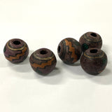Five brown ceramic beads with decorative patterns on a white background