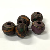 Five rustic beads with brown, purple, and green patterns on a white background