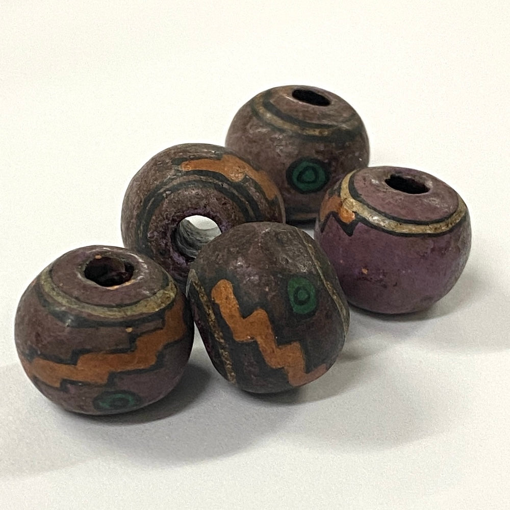 Five vintage-style ceramic beads with brown, green, and purple hues on a white background