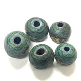 Five blue-green ceramic beads with textured surface on a white background