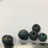 textured beads with motifs on a white background with a ruler for scale.