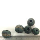 Five antique beads with textured surface and central hole on a white background, with a ruler for scale.