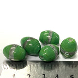 Green oval beads with silver swirls on a white background, measured against a ruler.