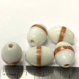 White beads with gold stripes on a white background with a ruler for scale.