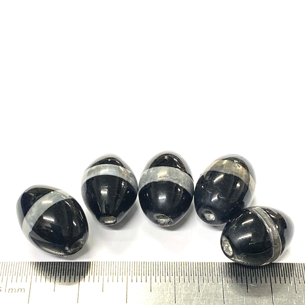 Black and silver beads with a ruler for scale on a white background