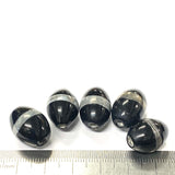 Black and silver beads with a ruler for scale on a white background