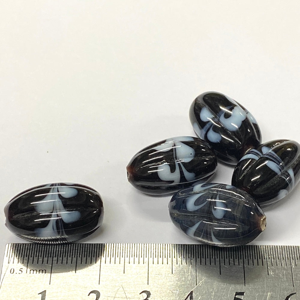 Black and white marbled beads with a ruler for scale on a white background