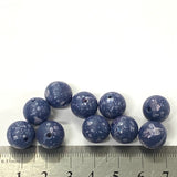 Blue speckled beads with a ruler for scale on a white background