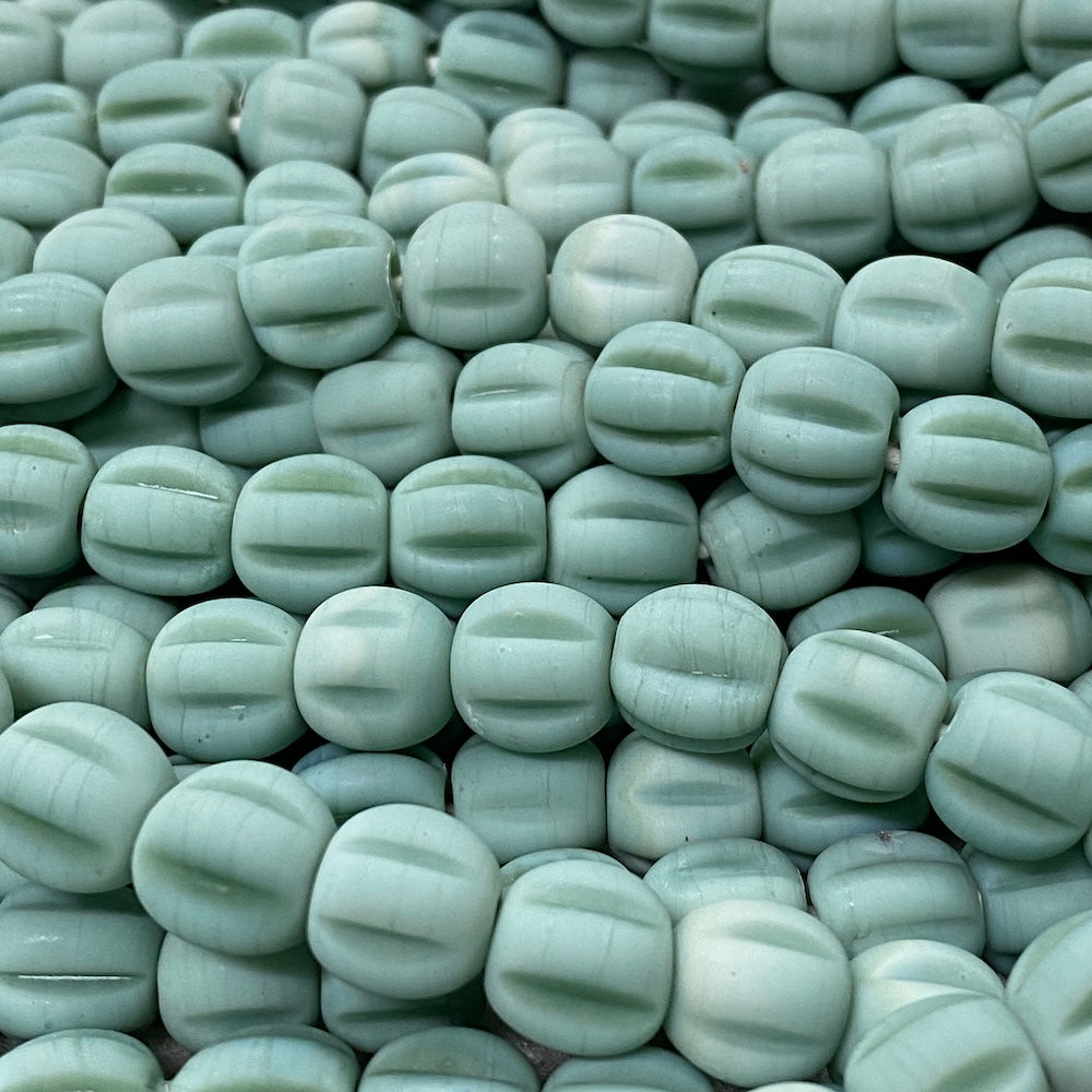 Close-up of light green glass melon shaped beads with a blurred background