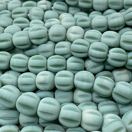 Close-up of light green glass melon shaped beads with a blurred background
