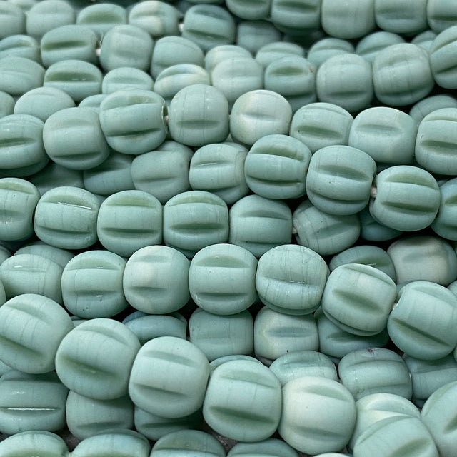 Close-up of light green glass melon shaped beads with a blurred background