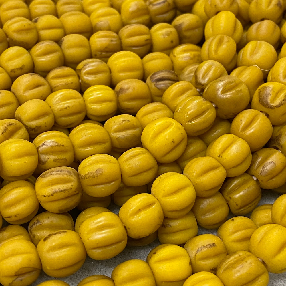 Close-up of mustard yellow glass melon shaped beads with a blurred background