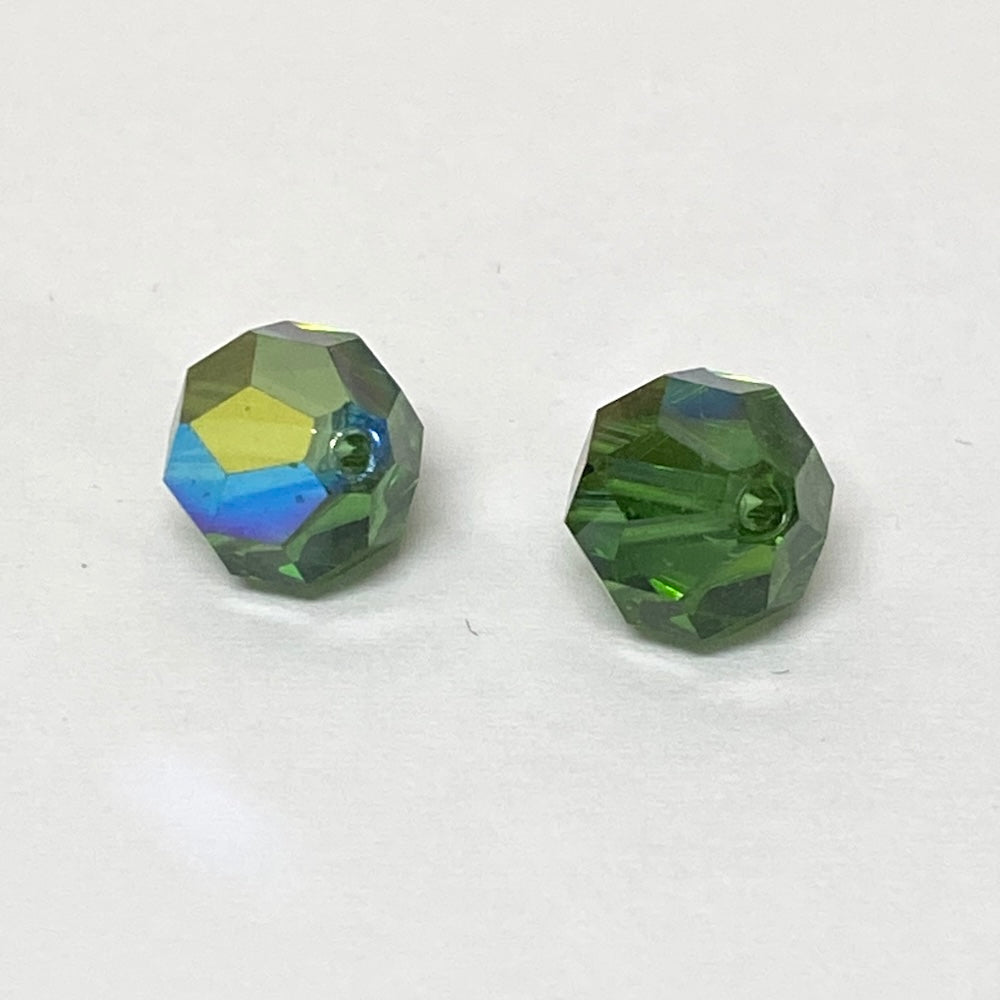 Two faceted green crystal beads on a white background