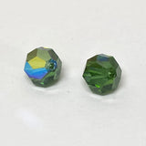 Two faceted green crystal beads on a white background