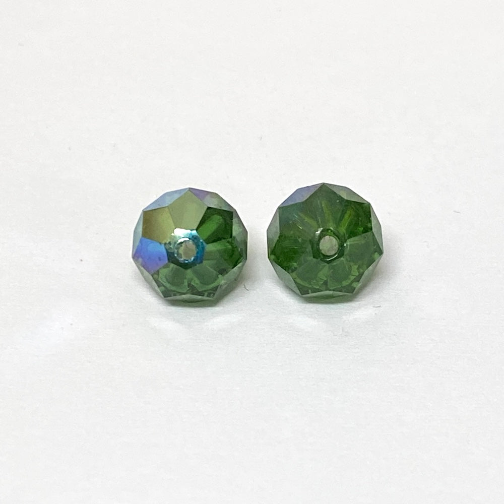 Two faceted green crystal beads on a white background