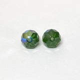 Two faceted green crystal beads on a white background