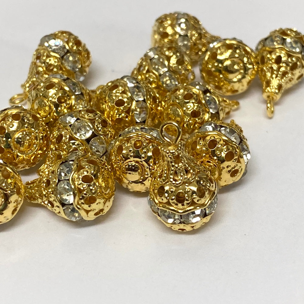 Group of gold and crystal pear shaped pendant beads on a white background