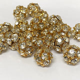 group of gold and crystal beads on a pin on a white background