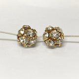 Pair of gold and crystal beads on a pin on a white background